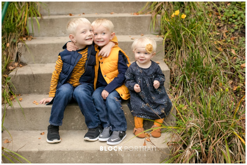 3 kids sitting on staircase posing for a Mpls Photographer outside Block Portrait Studios