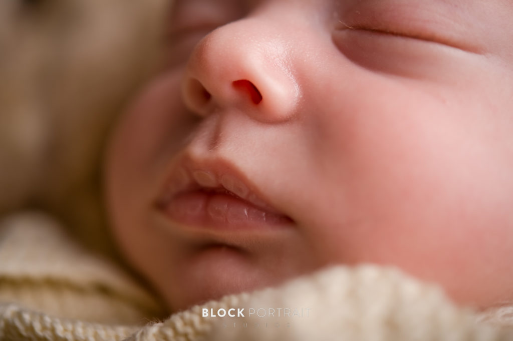 A close-up photo of a sleeping baby's face, with tan blankets surrounding them taken by newborn photographer Block Portrait Studios in Saint Paul Minnesota.