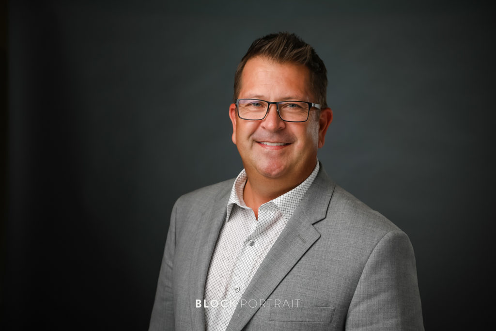 Man in gray suit with a dark background, professional business headshots, by Block Portrait Studios, Minnesota