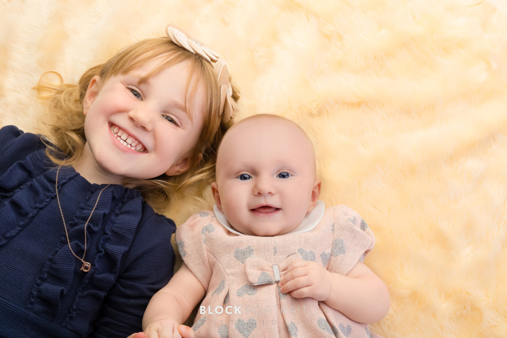 Picture of two girls smiling at the camera for Block Portrait Studios who provided a photo shoot survival kit.