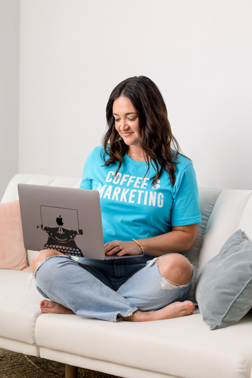 Twin Cities marketing specialist working on her laptop on a white couch at St. Paul photography studio Block Portrait Studios