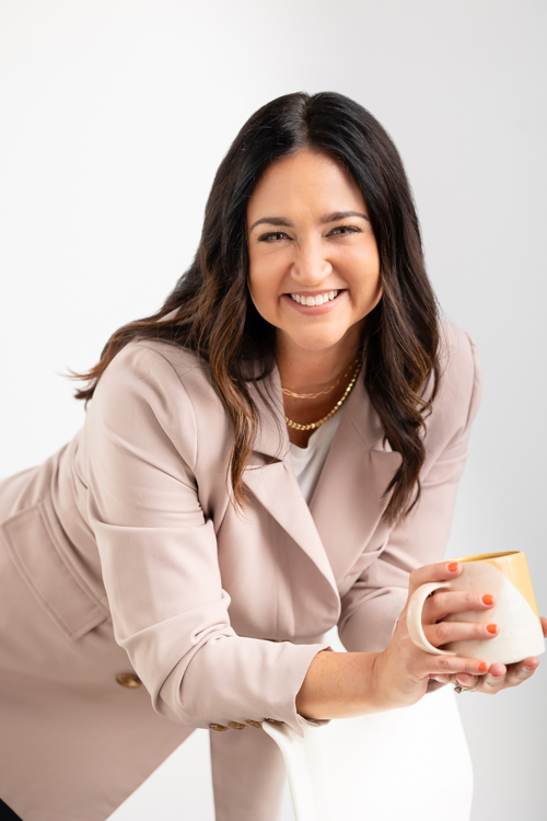 Woman holding coffee and smiling at photographer at Twin Cities Block Portrait Studios