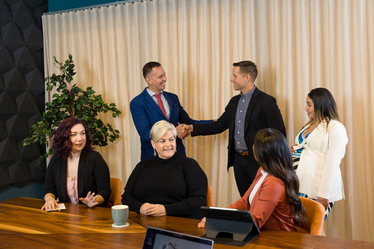 Team shaking hands and gathering at conference table in St. Paul. Photography by Block Portrait Studios