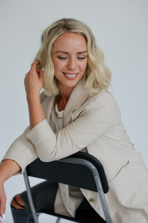 St. Paul Graphic designer smiling while posed on chair for photographer Block Portrait Studios