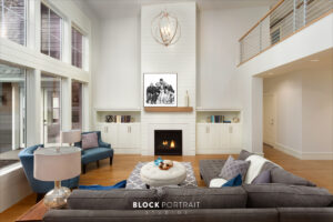 Image of a leaving room area with a fire place, wooden floor, and couches, with a black and white family portrait displayed on their wall.