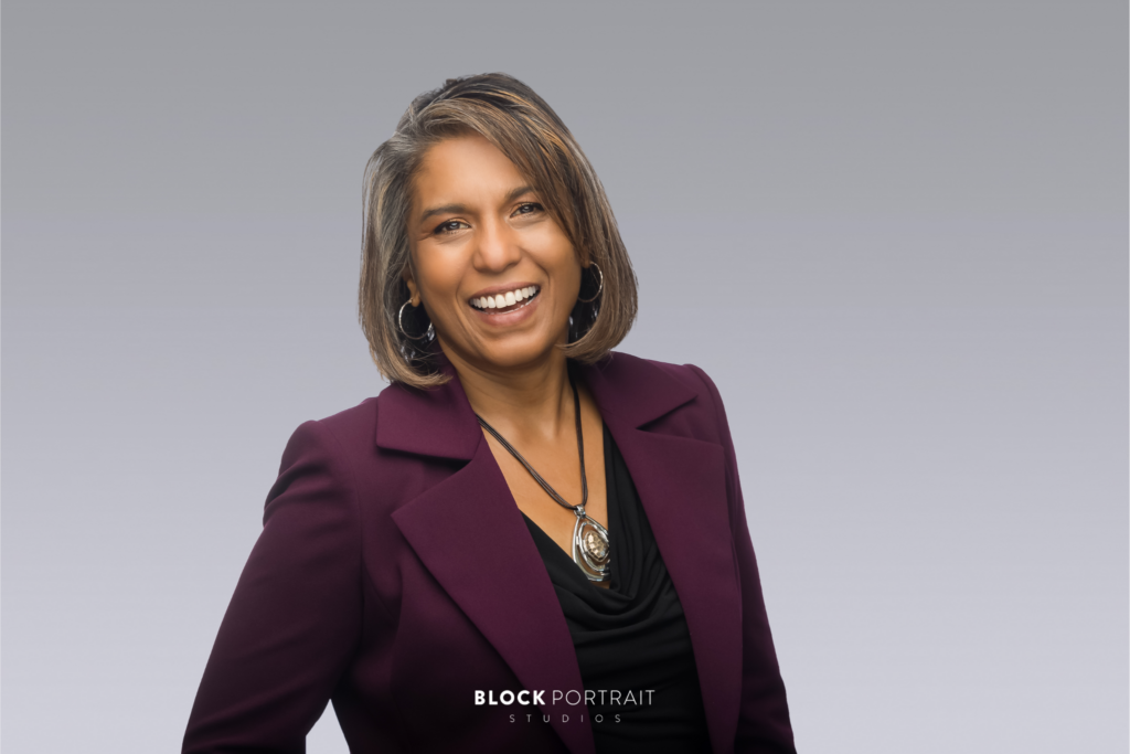 Professional portrait of an African American woman with short brown hair, smiling at the camera, wearing a plum purple blazer, taken by Twin Cities headshot photographer.